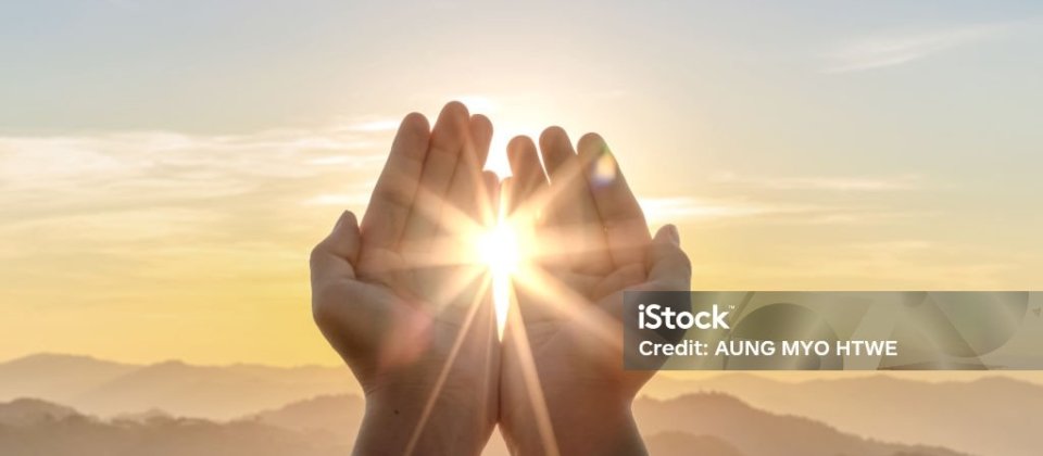 Human hands praying to god on mountain sunset background